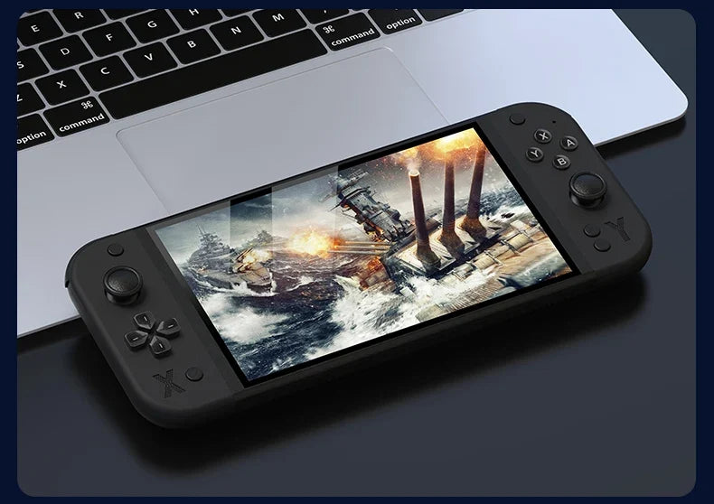 Handheld gaming console displaying a naval battle scene on a laptop keyboard.
