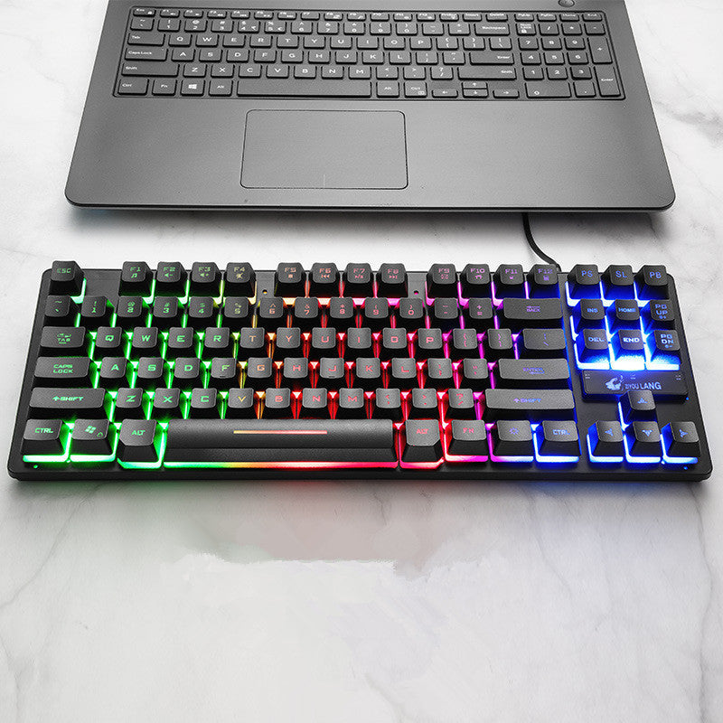 Mechanical keyboard with RGB lighting in front of a laptop on a white surface