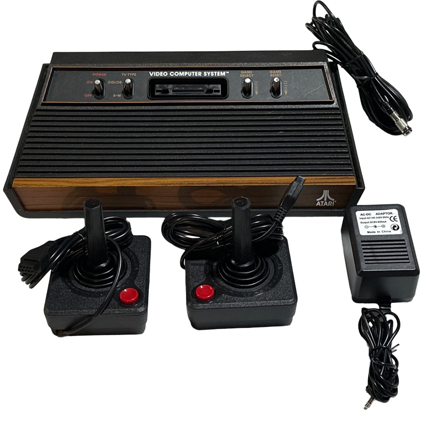 Atari Video Computer System with two joysticks and power supply on a white background