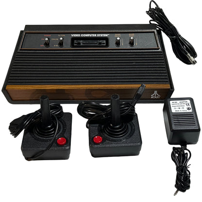 Atari Video Computer System with two joysticks and power supply on a white background