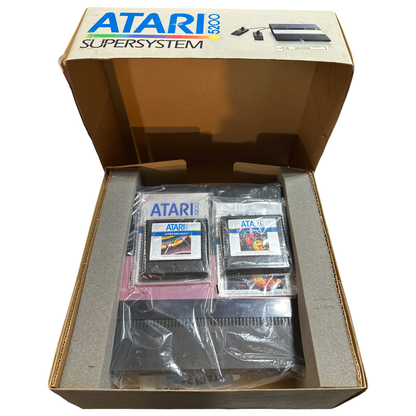Open Atari 5200 SuperSystem console box displaying the vintage game console, original foam inserts, manuals, and two Atari game cartridges in protective plastic packaging.