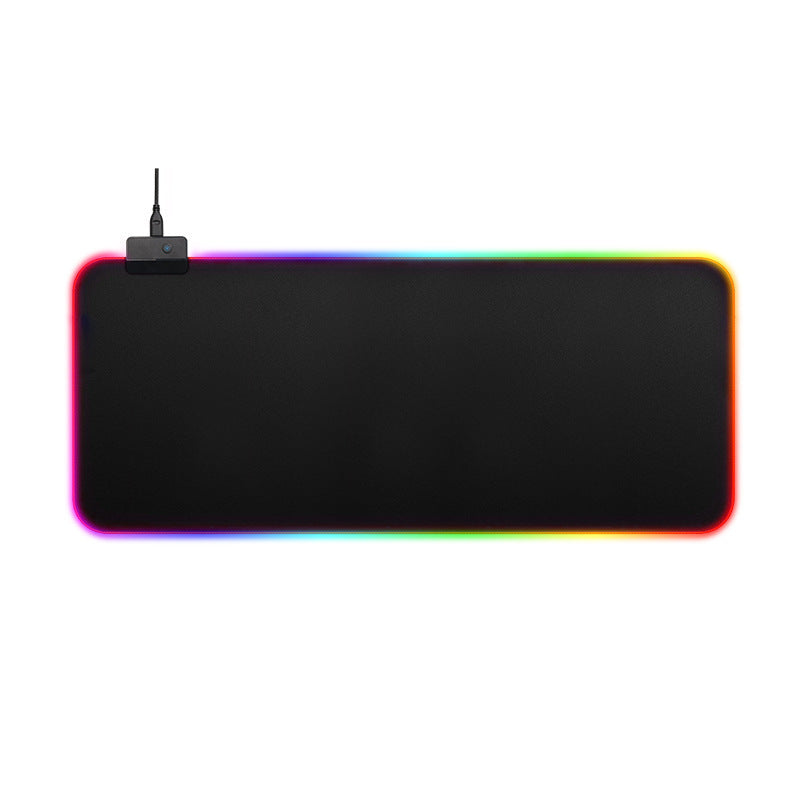 A large rectangular black desk mat or gaming pad with rounded corners, shown on a plain white background. A small black device with an antenna is attached near the top-left corner, and the mat is illuminated with a rainbow-colored LED border. Gaming Mouse Pad