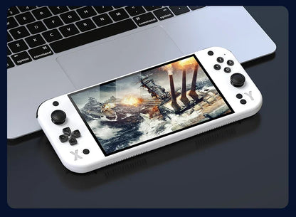 Handheld gaming console with a screen displaying a game, placed on a laptop keyboard. G90 Handheld Game Console – 7-inch 64GB Retro Arcade Gaming Device