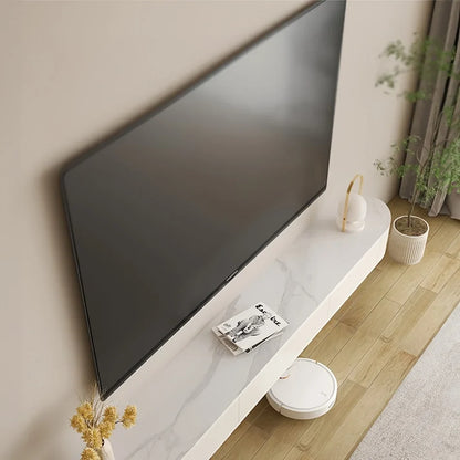 Modern living room with a large flat-screen TV on a white console table, a robot vacuum cleaner, and decorative items.