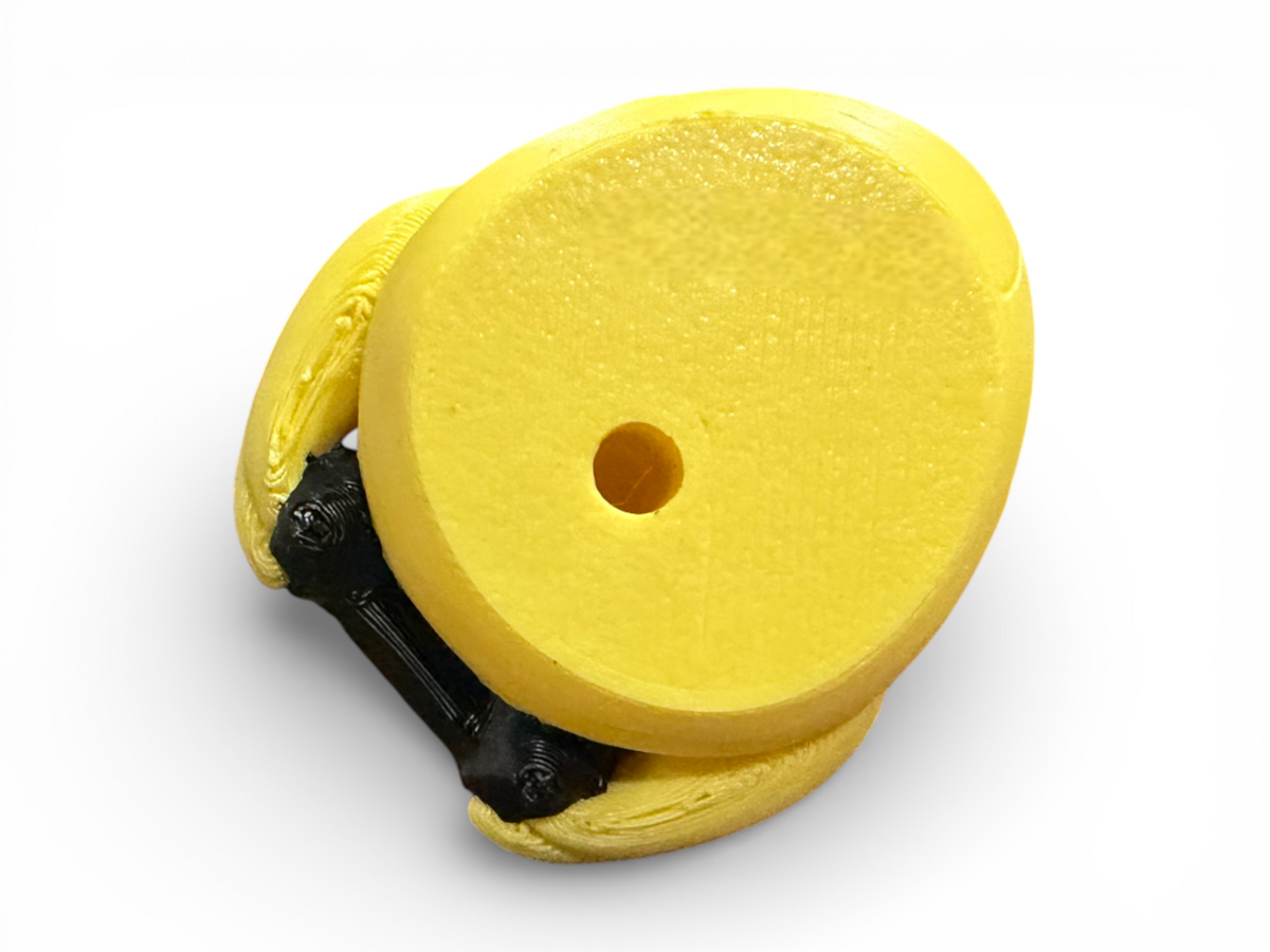 A bright yellow circular foam or rubber disc with a central hole, shown with a black mounting bracket or hardware underneath, isolated on a white background.