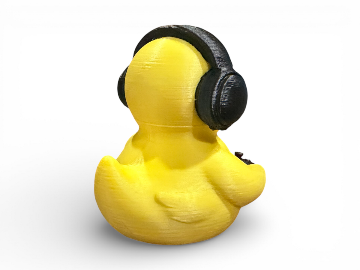 A yellow rubber duck viewed from the back, wearing a black headphone accessory, isolated on a white background.