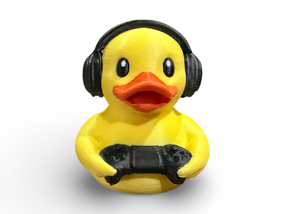 A yellow rubber duck toy wearing black headphones and holding a black game controller, shown against a plain white background.