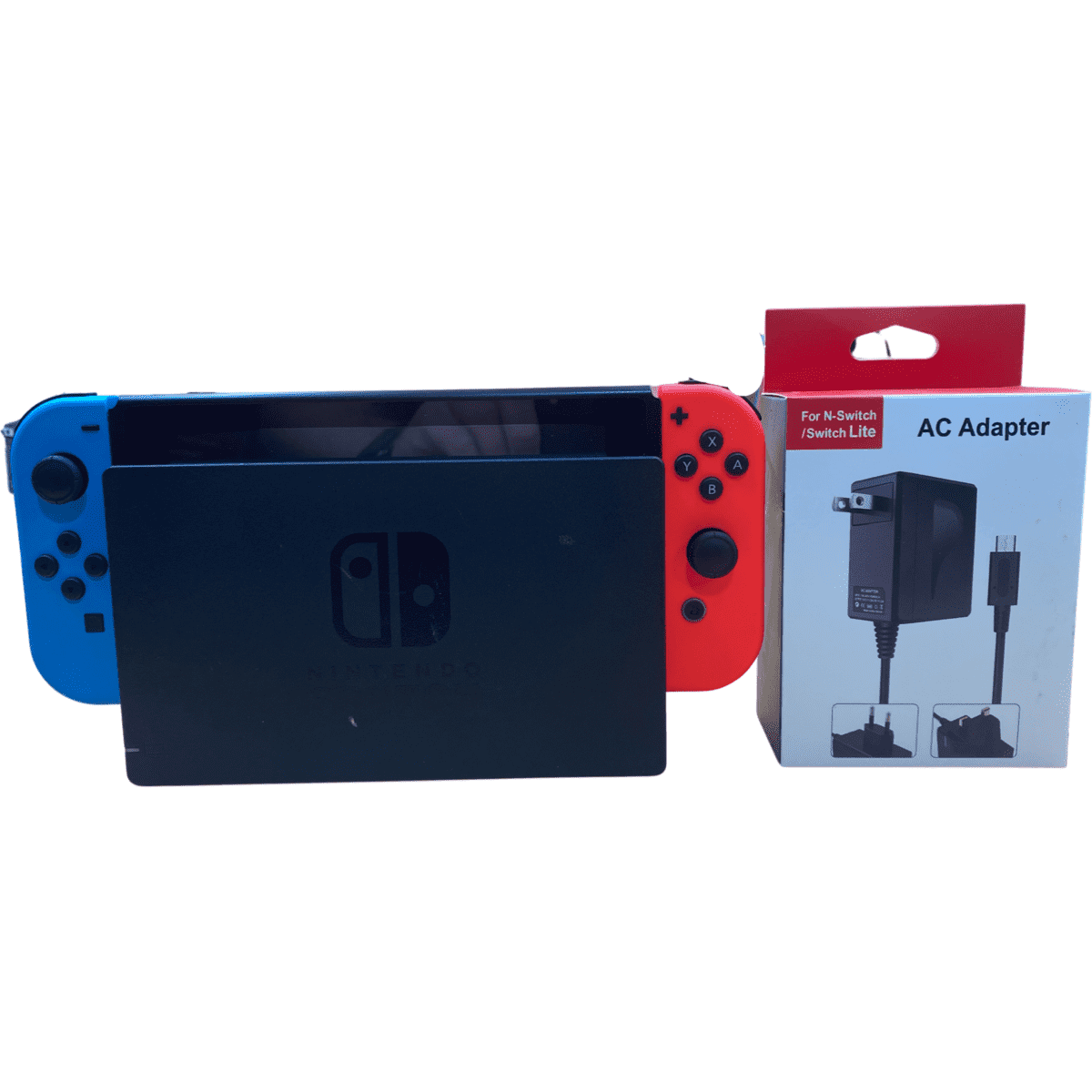 Nintendo Switch console with blue and red Joy-Con and AC adapter packaging on a white background
